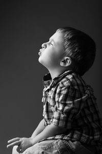 Cute boy making face against black background