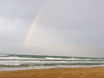 Scenic view of rainbow over sea against sky