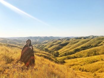 Woman standing on agricultural field against sky