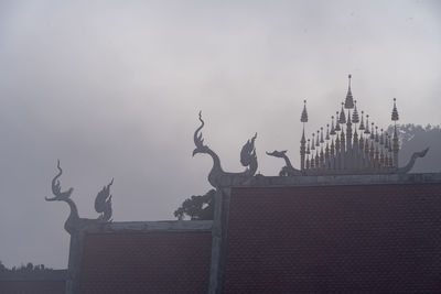 Sculpture of building against cloudy sky