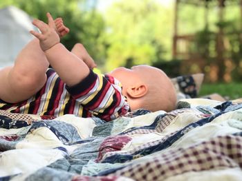 Side view of baby boy relaxing on picnic blanket