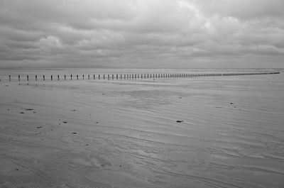 Scenic view of a beach against dramatic sky at low tide on a cloudy, gloomy and windswept day.