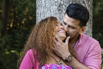 Man kissing smiling woman in park