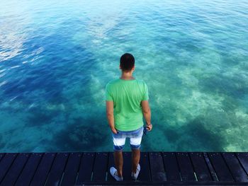 Rear view of man standing on pier over sea