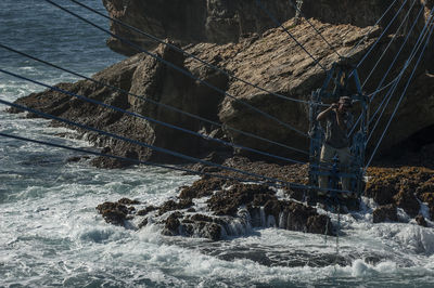 Man on overhead cable car over sea