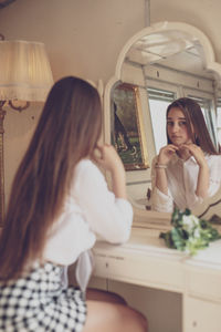 Woman sitting in front of mirror at home