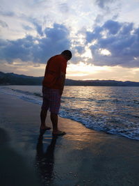 Full length of man standing on beach during sunset