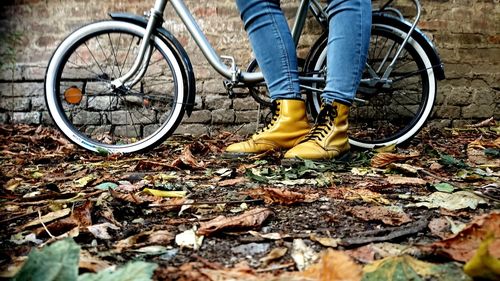 Low section of woman wearing shoes while standing by bicycle outdoors