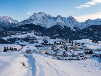 Scenic view of snow covered mountain by alpine village against sky