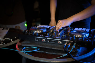 Midsection of man operating sound mixer at nightclub