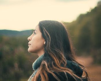 Young woman looking away against sky