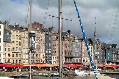 Sailboats in city by buildings against sky