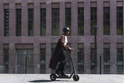 Businesswoman riding electric push scooter on sunny day