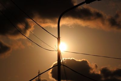 Low angle view of silhouette electricity pylon against sky during sunset