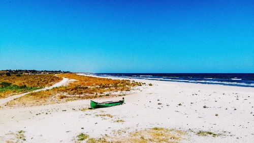 Scenic view of beach against clear blue sky