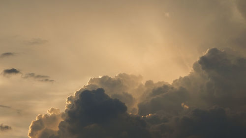 Low angle view of sunlight streaming through clouds