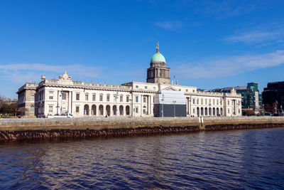 View of building by river against blue sky