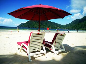 Deck chairs on beach against sky