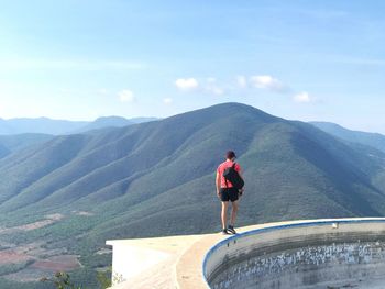 Rear view of man on mountain against sky