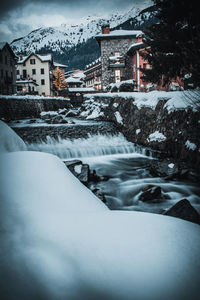 Snow covered houses by buildings in city