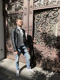 Portrait of young man standing against door