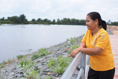 Side view of woman looking at shore against sky