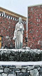 Statue against brick wall