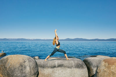 Young woman practicing yoga on lake tahoe in northern california.