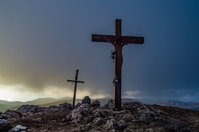 Low angle view of cross on mountain against sky