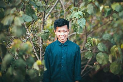Portrait of young man standing against plants