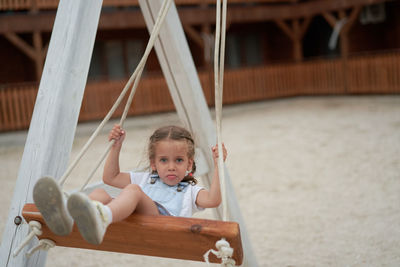 Portrait of cute boy sitting on slide at playground