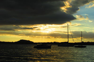 Silhouette sailboats in sea against sky during sunset