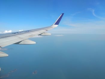 Airplane flying over sea against blue sky