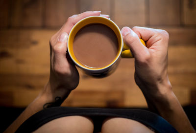 High angle view of woman holding coffee in cup
