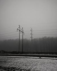 Electricity pylon on field against sky during winter