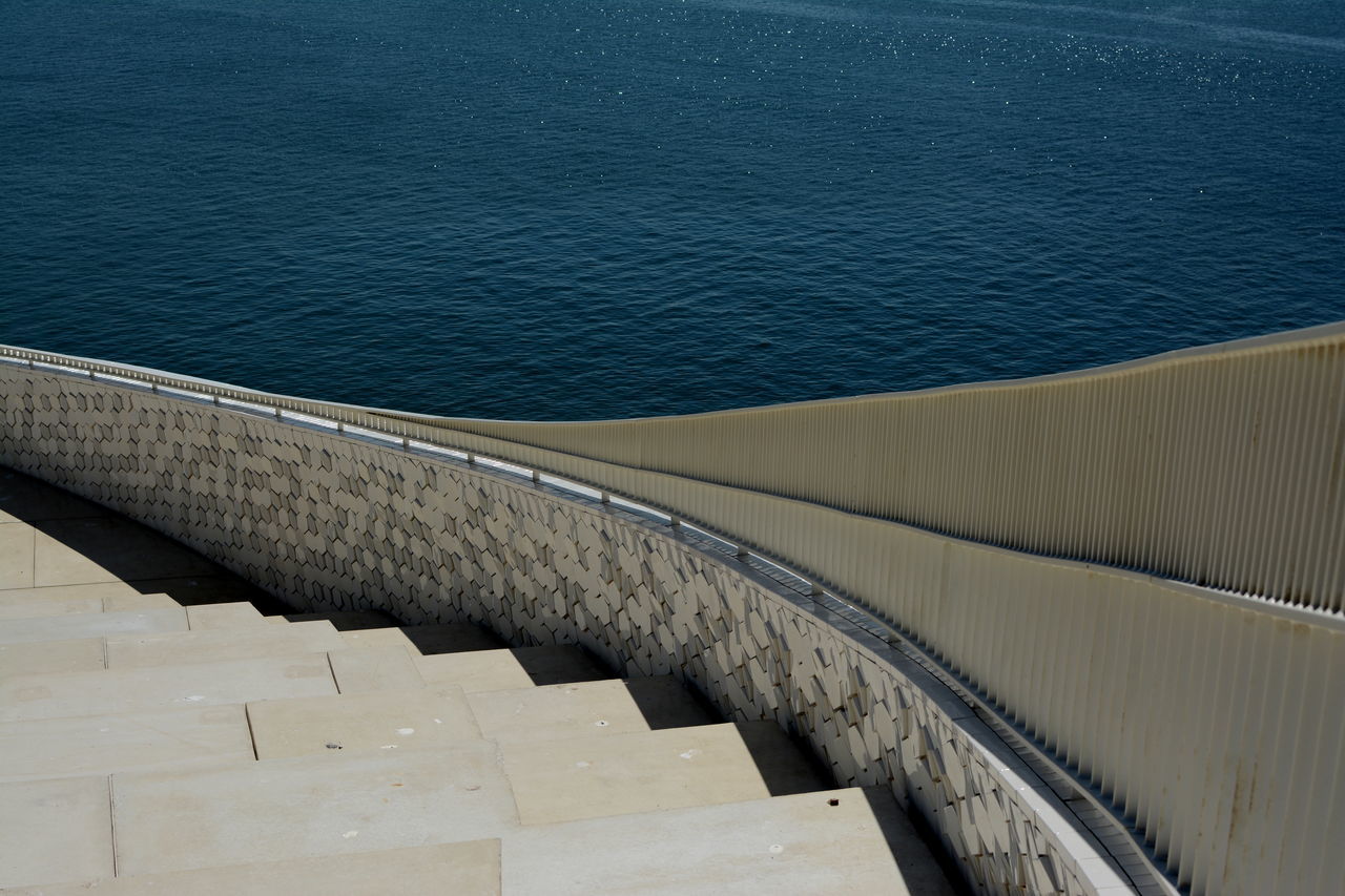 water, built structure, architecture, high angle view, sea, transportation, blue, connection, part of, railing, outdoors, no people, day, bridge - man made structure, cropped, rippled, pier, bridge, nature, river