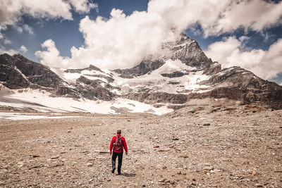 Rear view of people on snowcapped mountain against sky