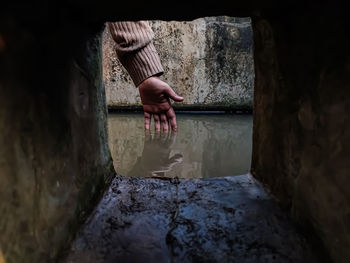 The reflection of a girl's hand fellon a water-filled cistern.