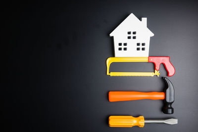 Directly above shot of plastic tools with model house on black background