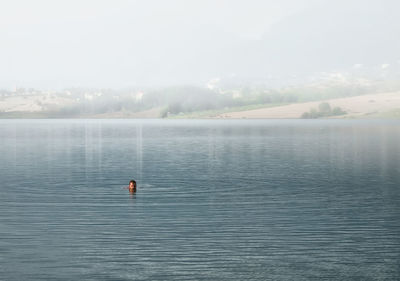 Person swimming in lake against sky