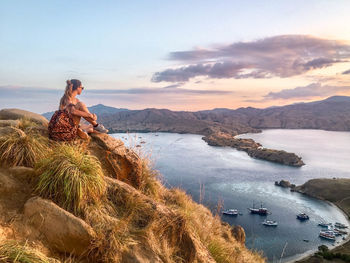 High angle view of woman sitting on mountain against sky