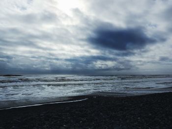 Scenic view of beach against cloudy sky