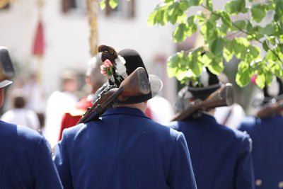 Rear view of males with rifle walking during sunny day