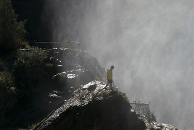 High angle view of man standing on mountain during foggy weather