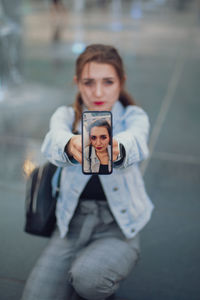 High angle view of woman showing photograph on mobile phone 