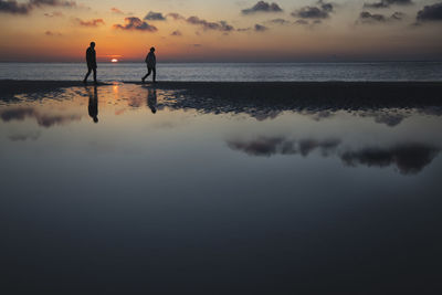 Hikers at beach low tide pool at sunset