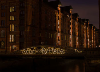 Illuminated bridge against buildings in city at night