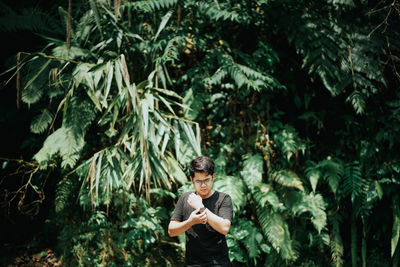 Young man standing against plants