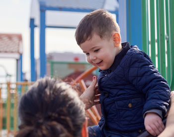 Toddler being helped to ride the slide on the playground