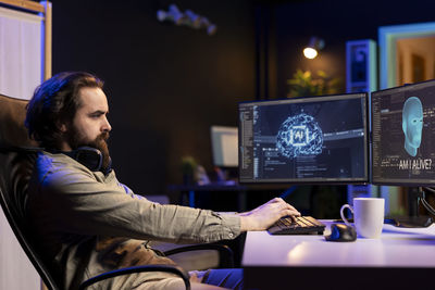 Side view of young man using laptop at home